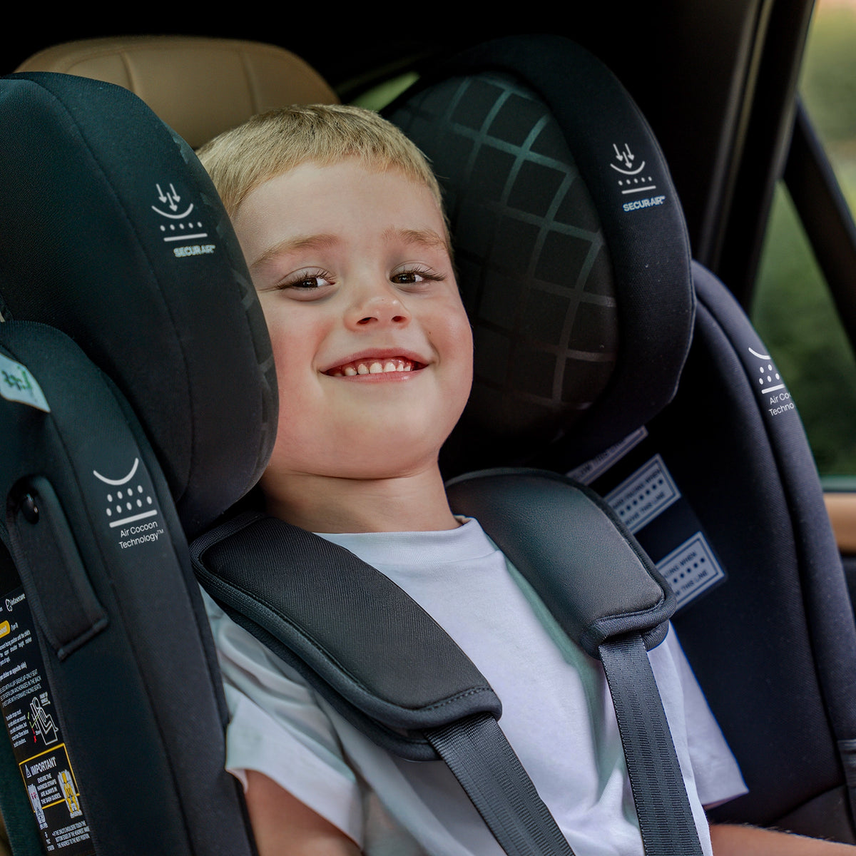 A young boy smiling while seated in the InfaSecure Quattro Onyx car seat  inside a vehicle.